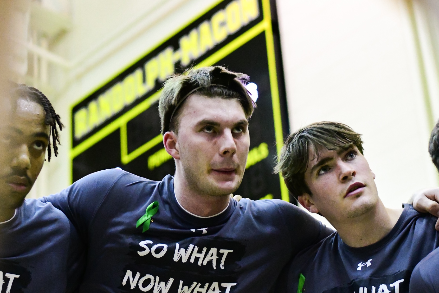 Randolph–Macon players in a tight huddle wearing "So What Now What" shirts