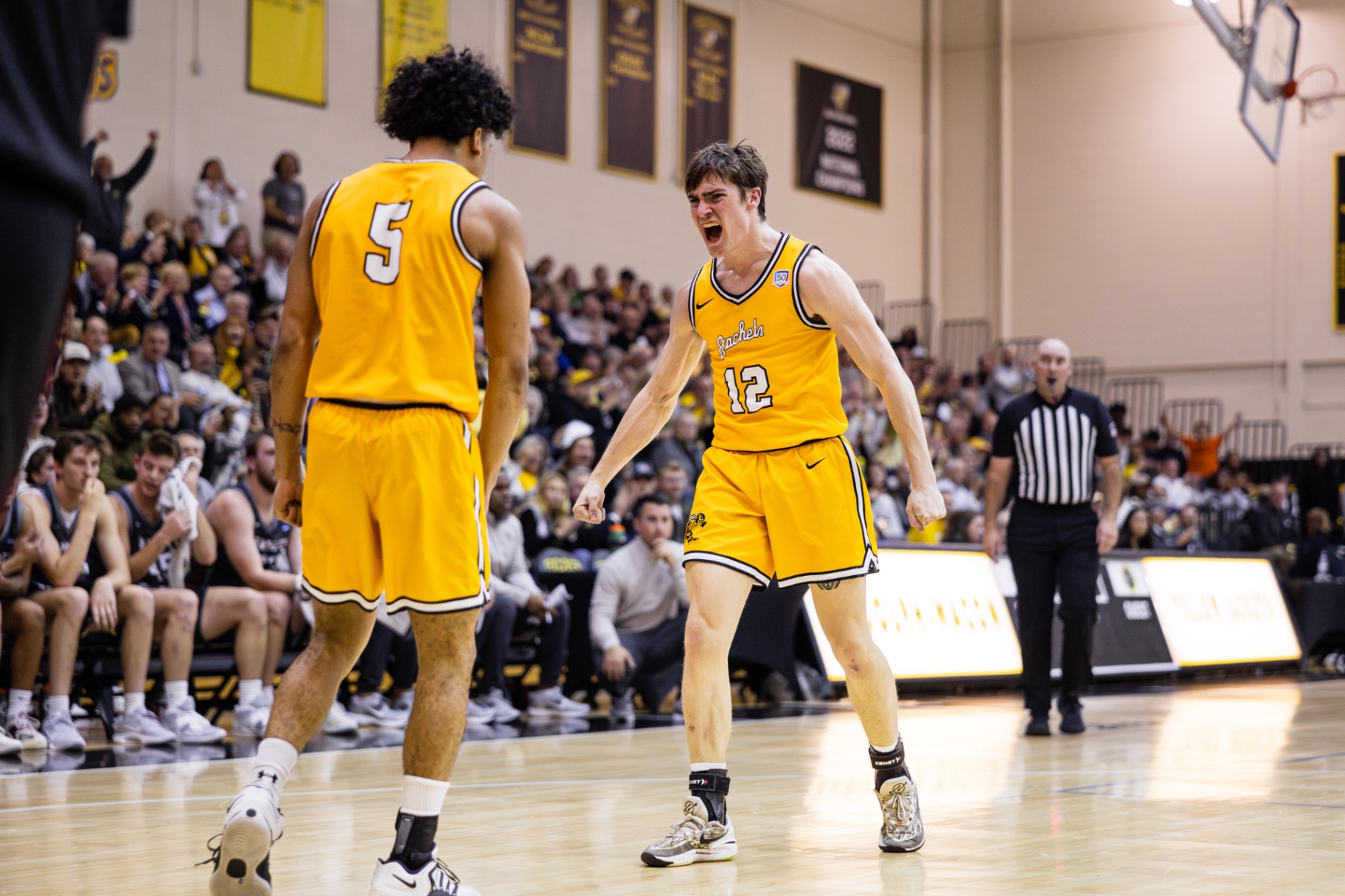 Randolph–Macon players in gold uniforms on the floor during a road game